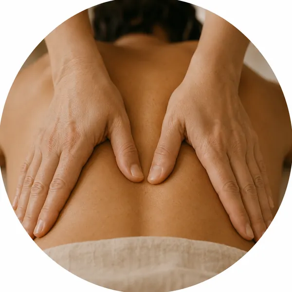 Grande plano das mãos de uma terapeuta a trabalhar os músculos das costas.
